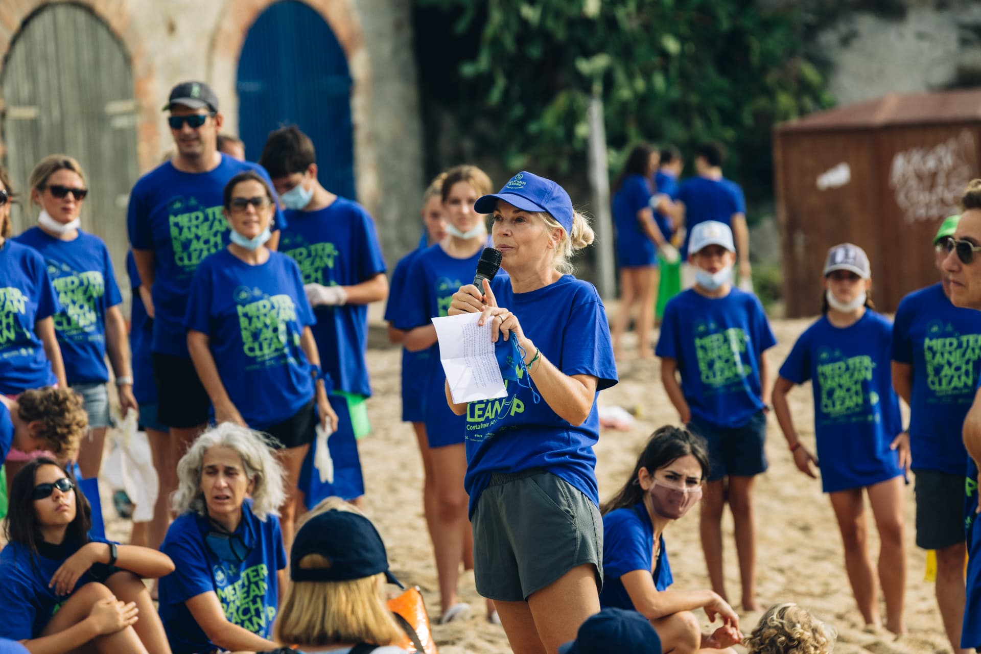 Mónica Navarro speaking with a microphone during a Mediterranean beach clean-up